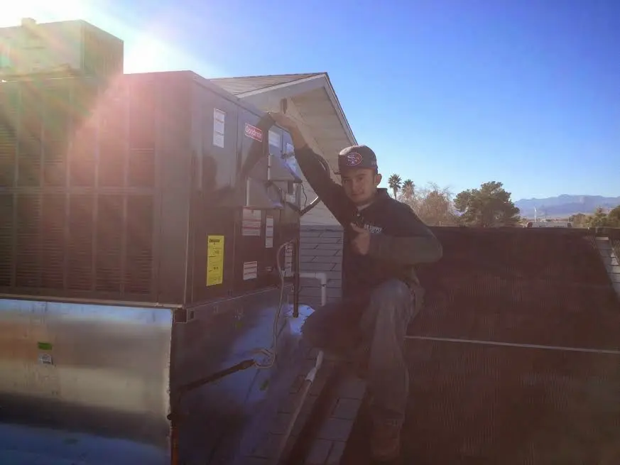 HVAC technician performing Air Duct Repair on a rooftop unit in Genoa